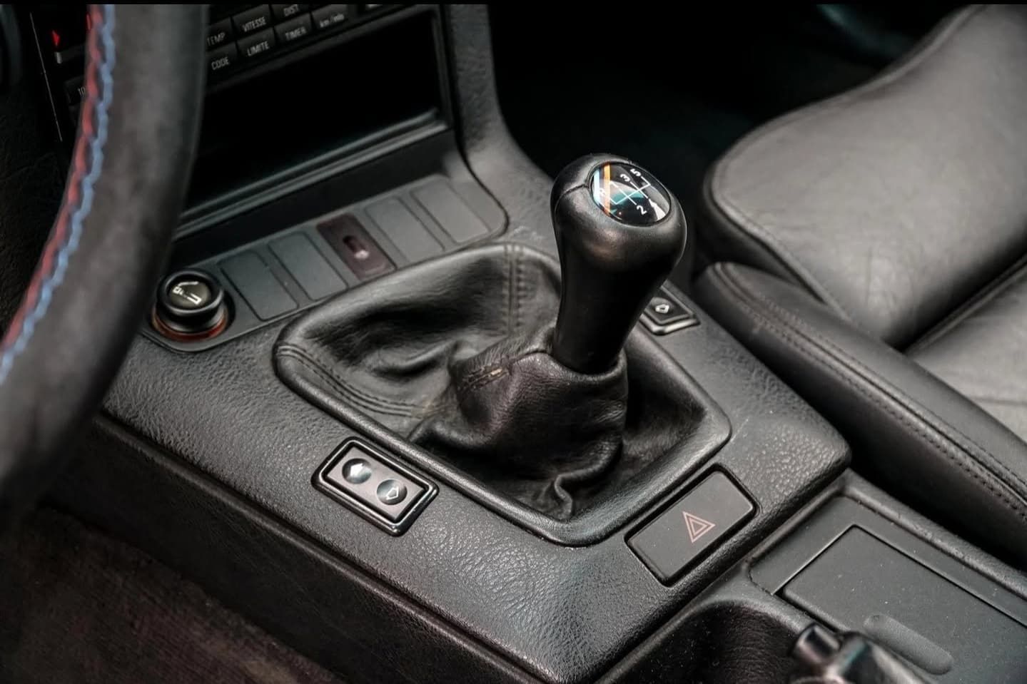 תקריב של תיבת הילוכים ידנית של BMW בפנים מכונית עור שחור.