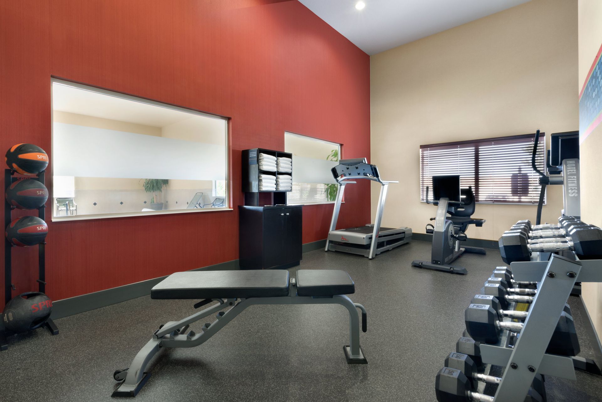 A gym with a treadmill a bench and dumbbells