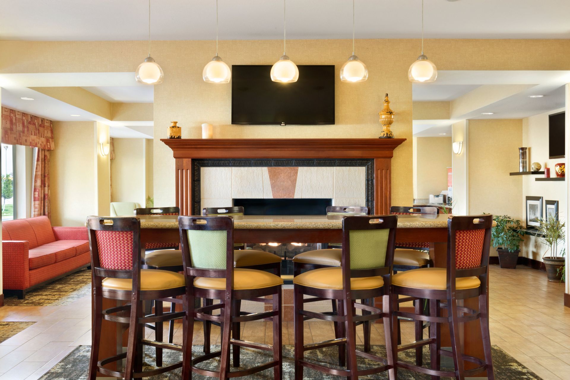 A hotel lobby with a fireplace , bar , chairs and a couch.