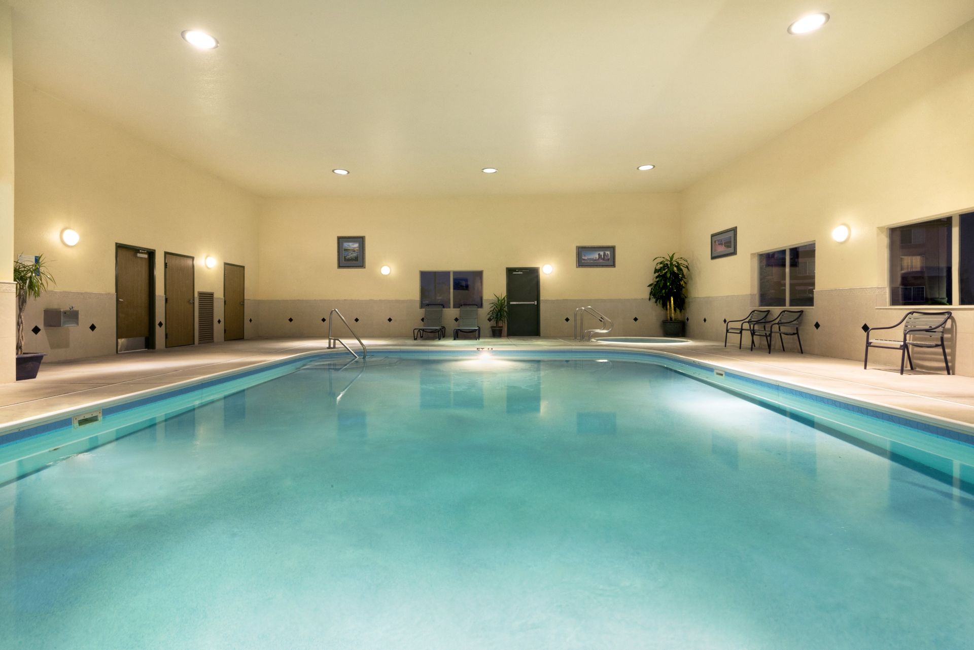 There is a large indoor swimming pool with chairs around it.