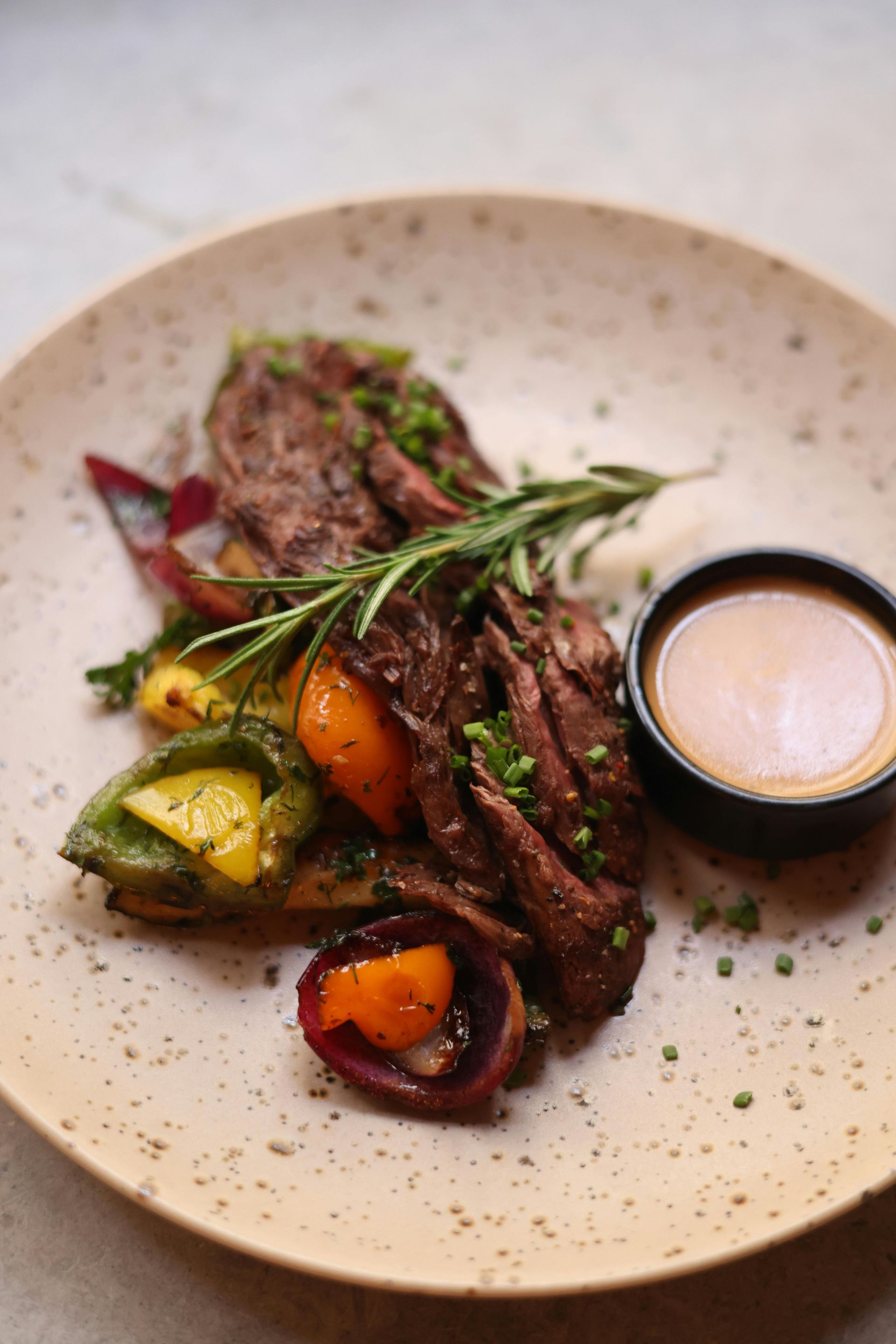 A close up of a plate of food with meat and vegetables on a table.