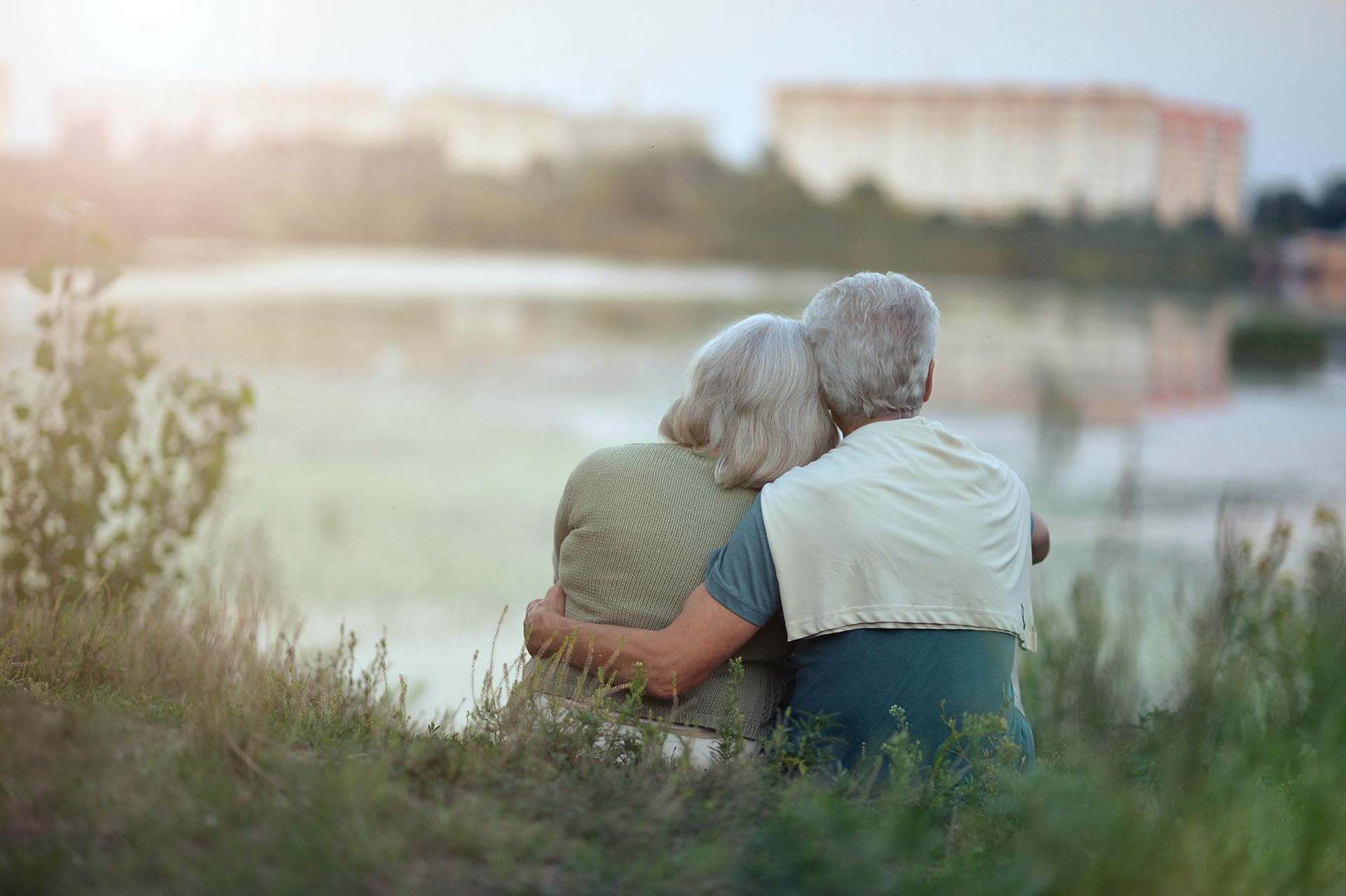 an elderly couple is sitting in the leaves under a tree .