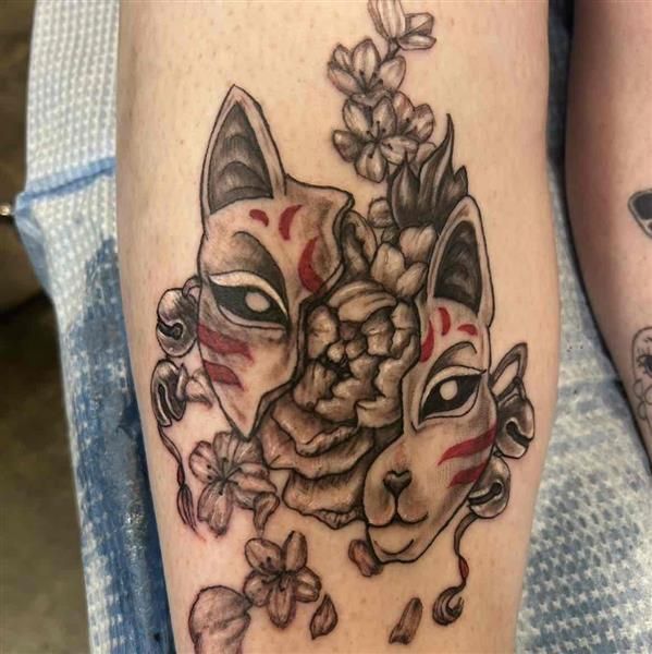 Tattoo of three stylized cat faces with flowers in black, red, and beige ink