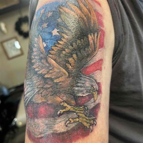 A watercolor tattoo design with flowing pigment and painterly color blending on a studio desk.