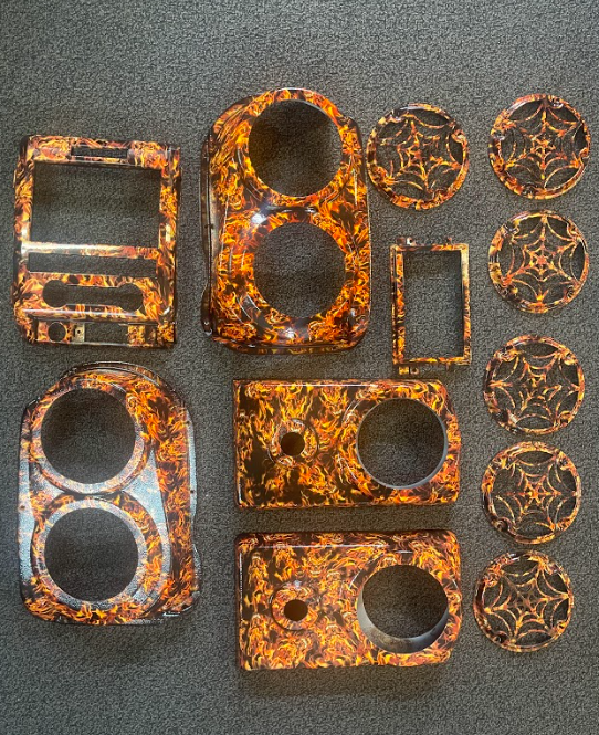 A collection of custom-painted automotive interior trim pieces featuring an orange and black marbled web design.