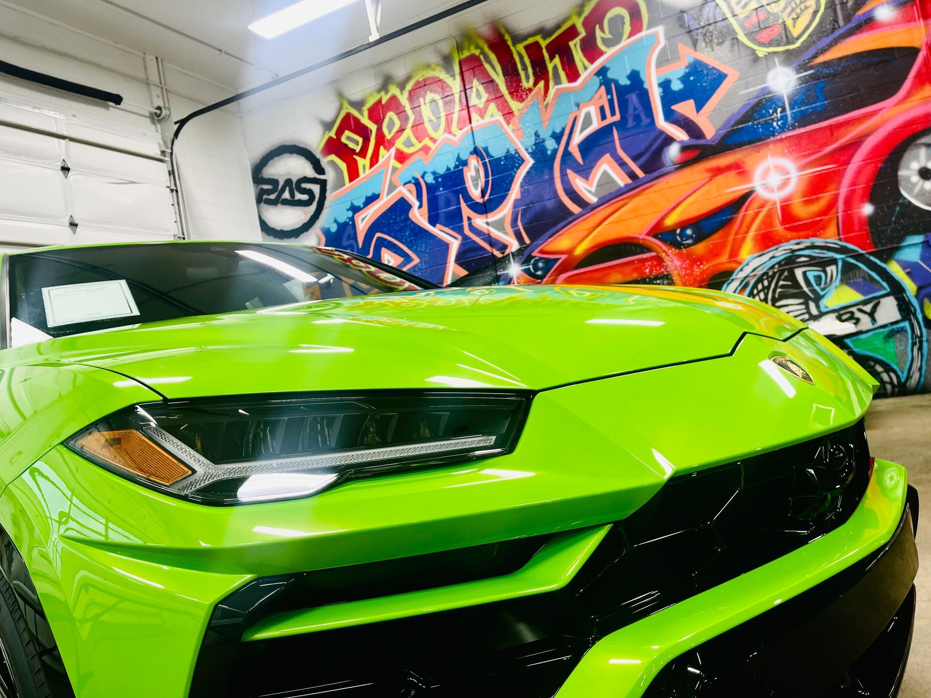 Cars in a garage with colorful graffiti art. Mechanics work on the vehicles.