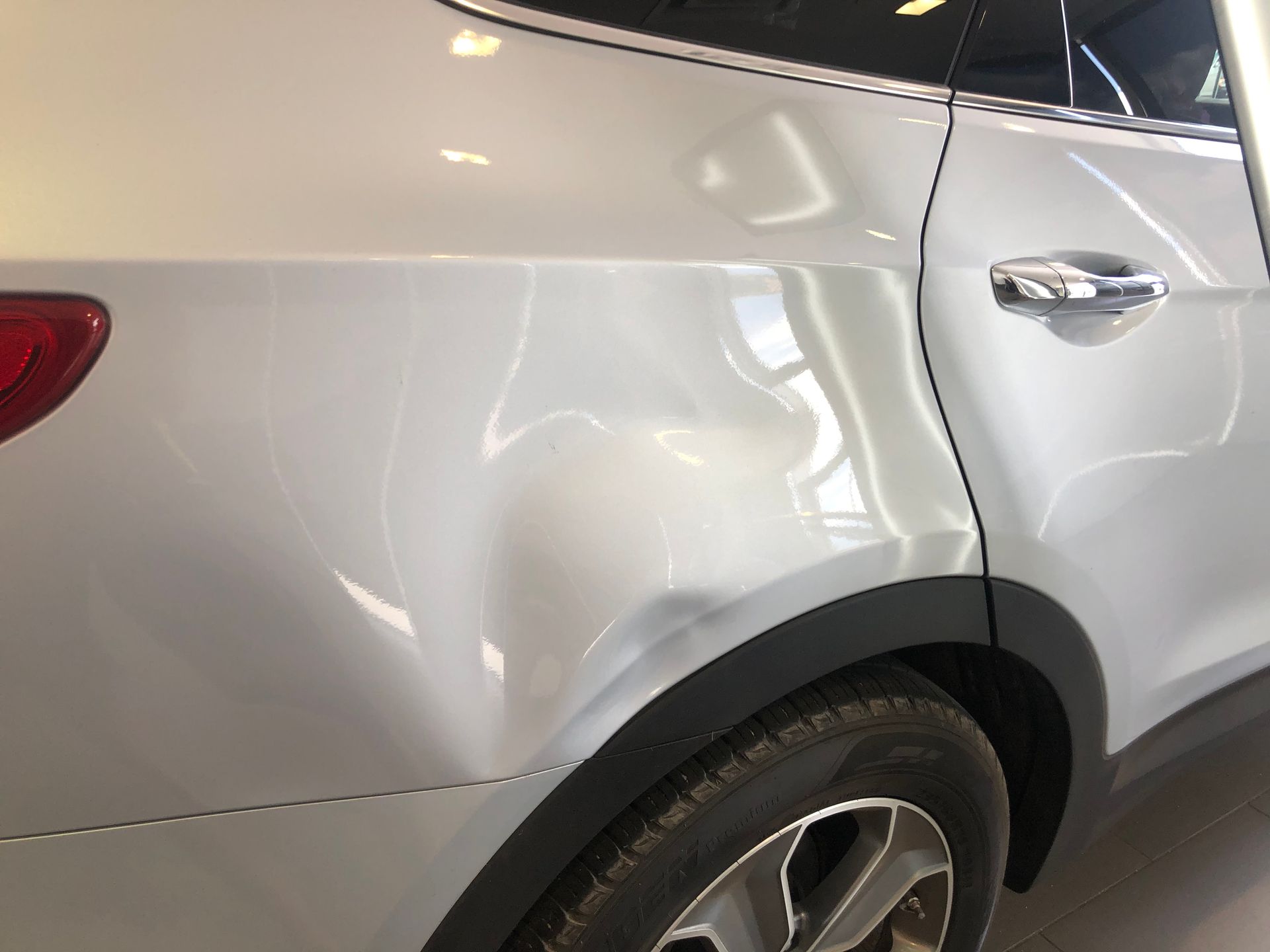 White SUV with a large dent on the rear passenger door and quarter panel