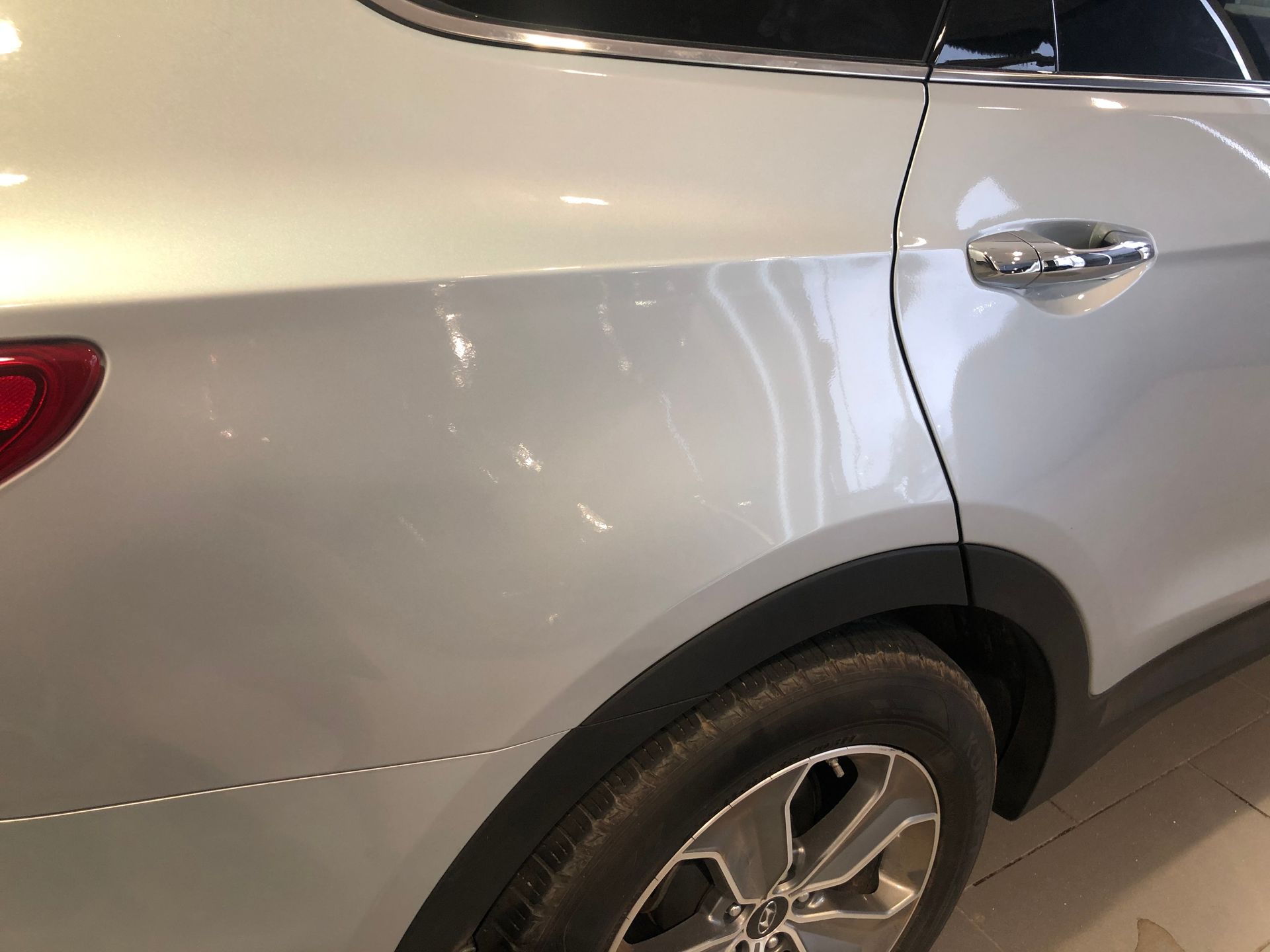 Silver SUV rear side close-up with rear wheel and door handle visible