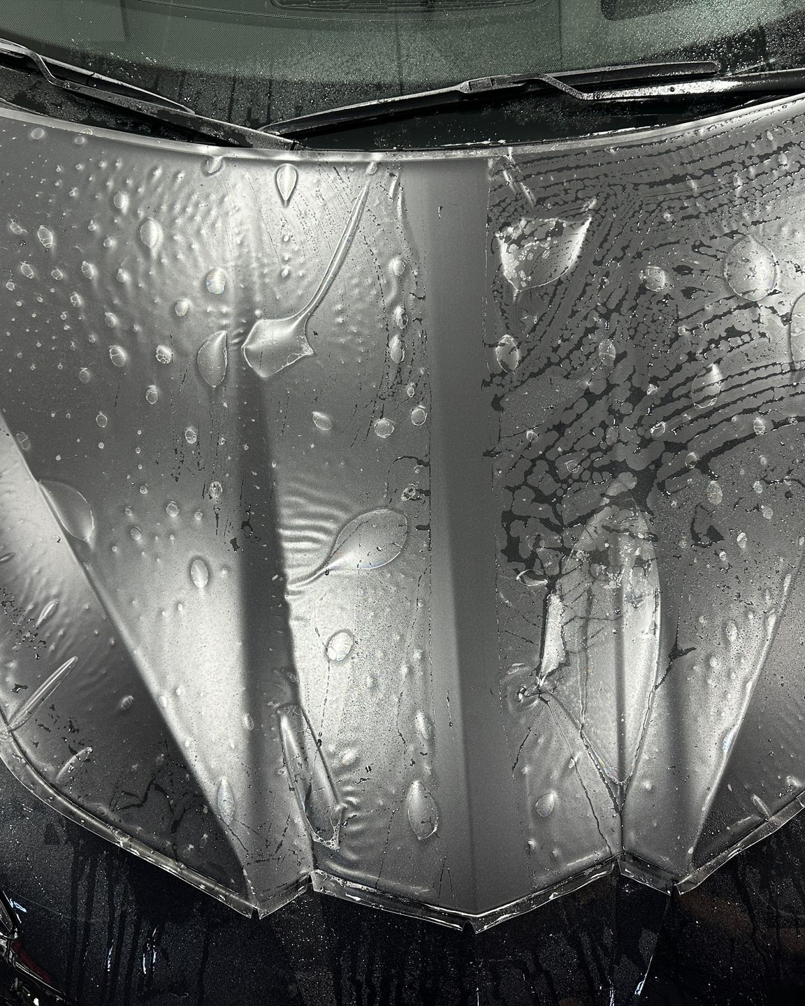 A person applying a clear protective film over a white car's side mirror.