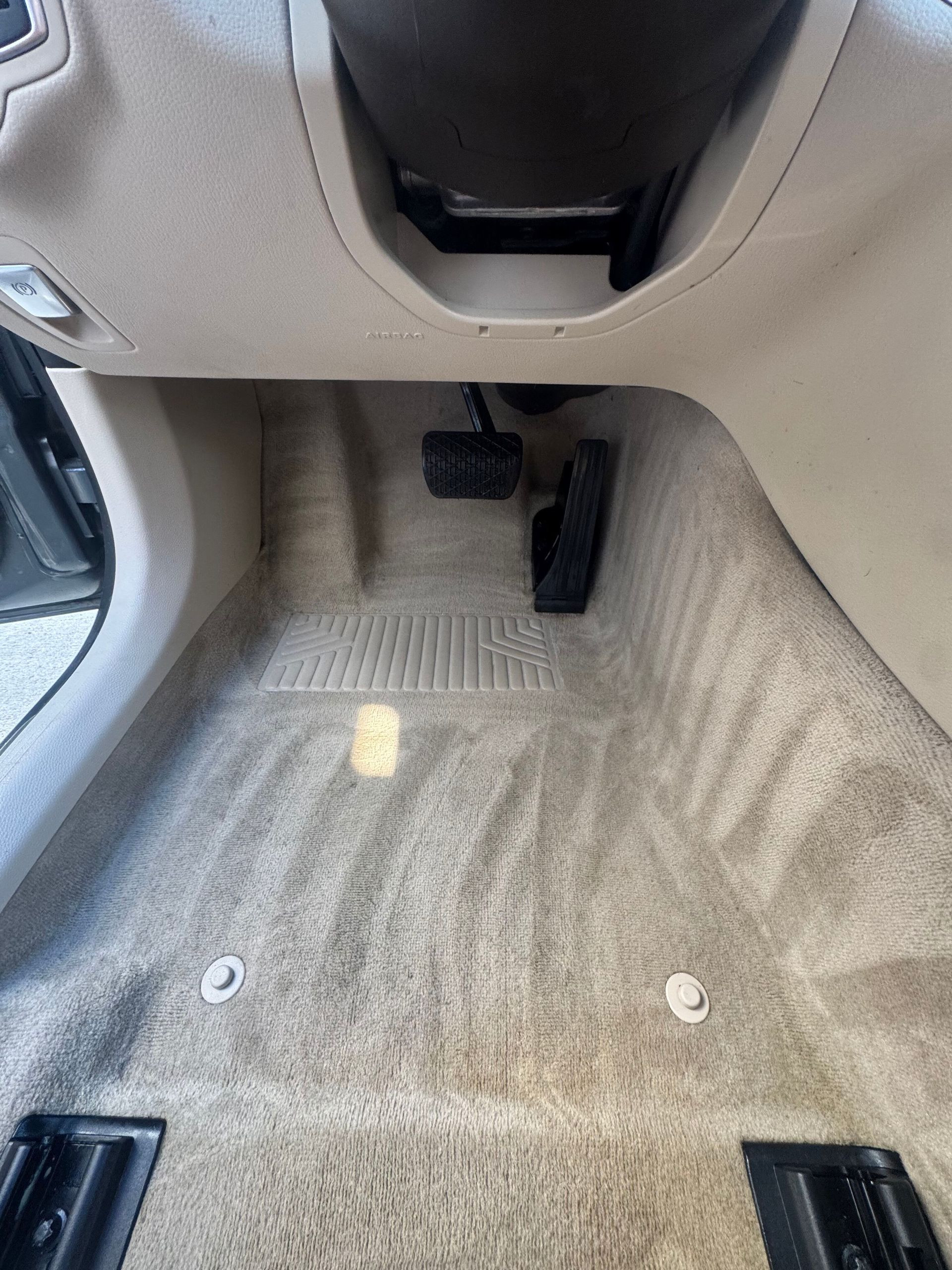 Vacuum nozzle cleaning a car’s black fabric seat, with a gloved hand in the background