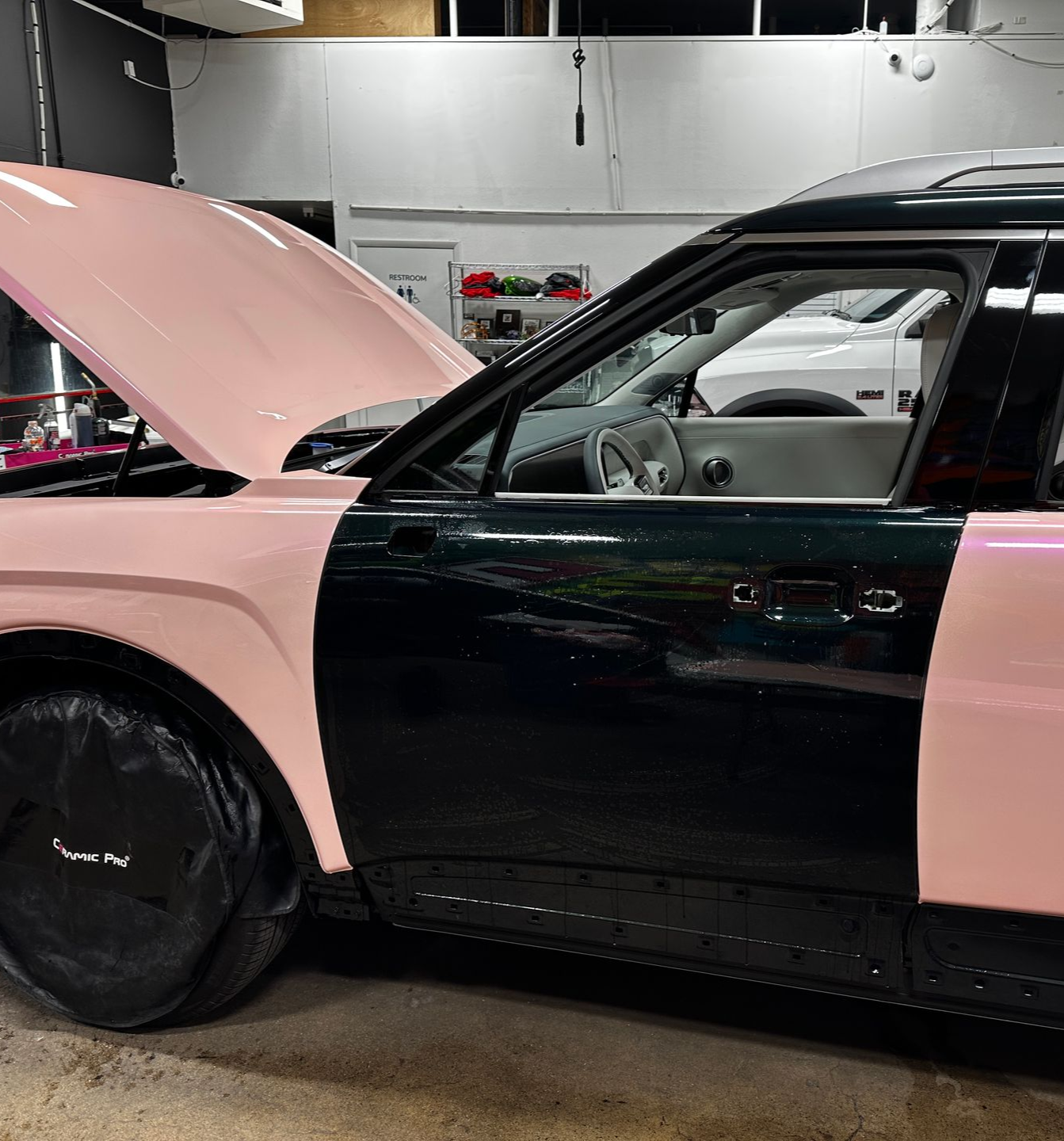 Pink and black car with hood open in a garage, side view
