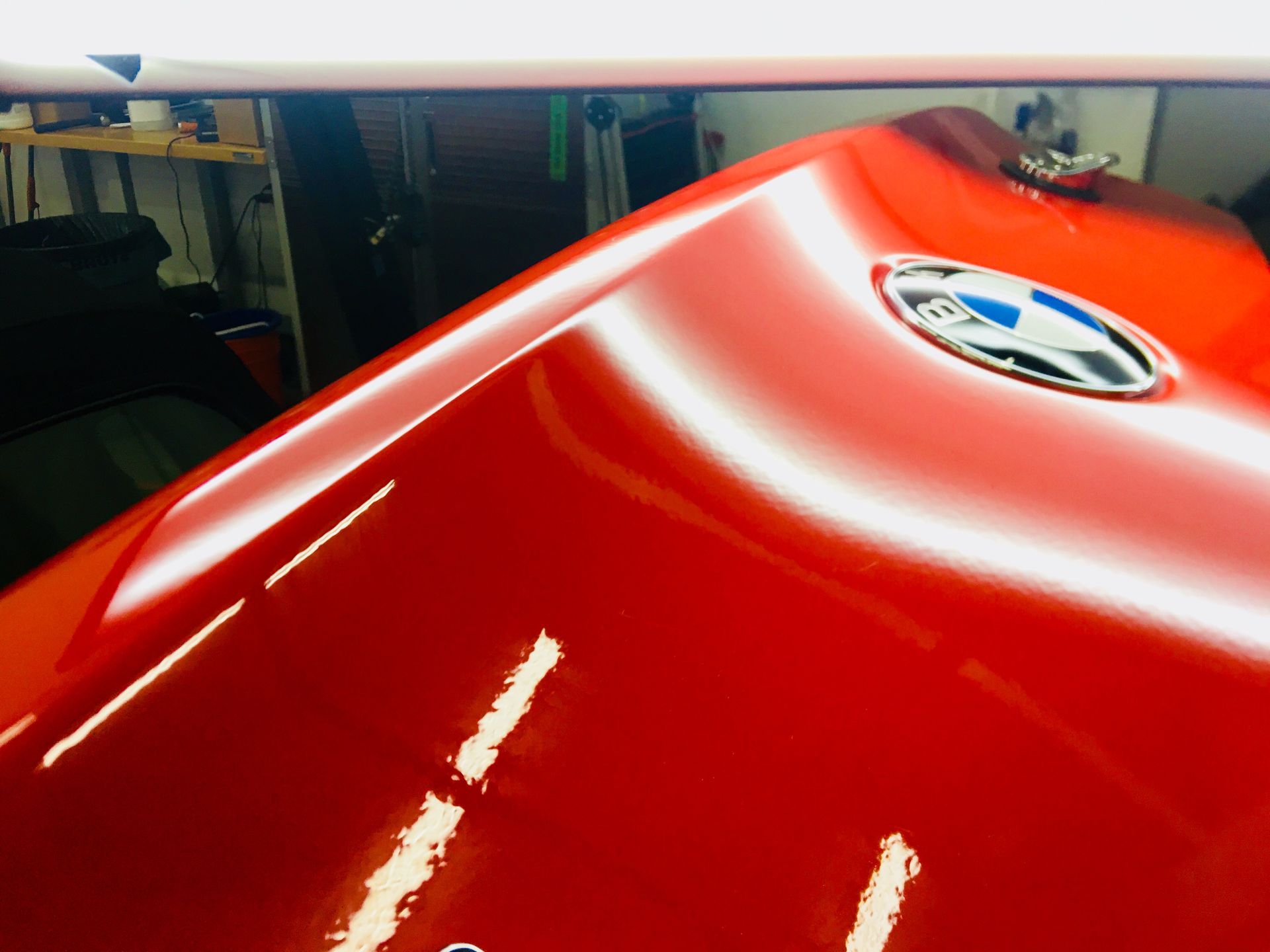 Close-up of a red BMW hood with the emblem visible indoors
