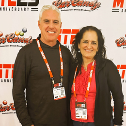Two people posing at an MIT-themed event backdrop, wearing lanyards and smiling.