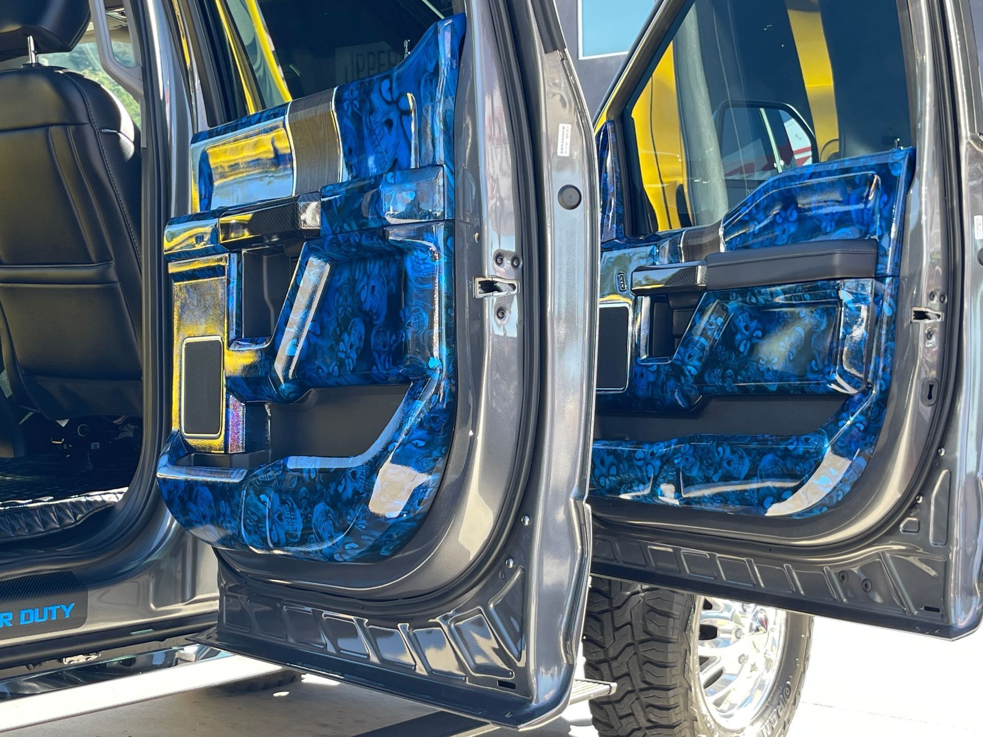 Car doors with blue patterned custom interior door panels visible, with an open view into the vehicle's cabin.