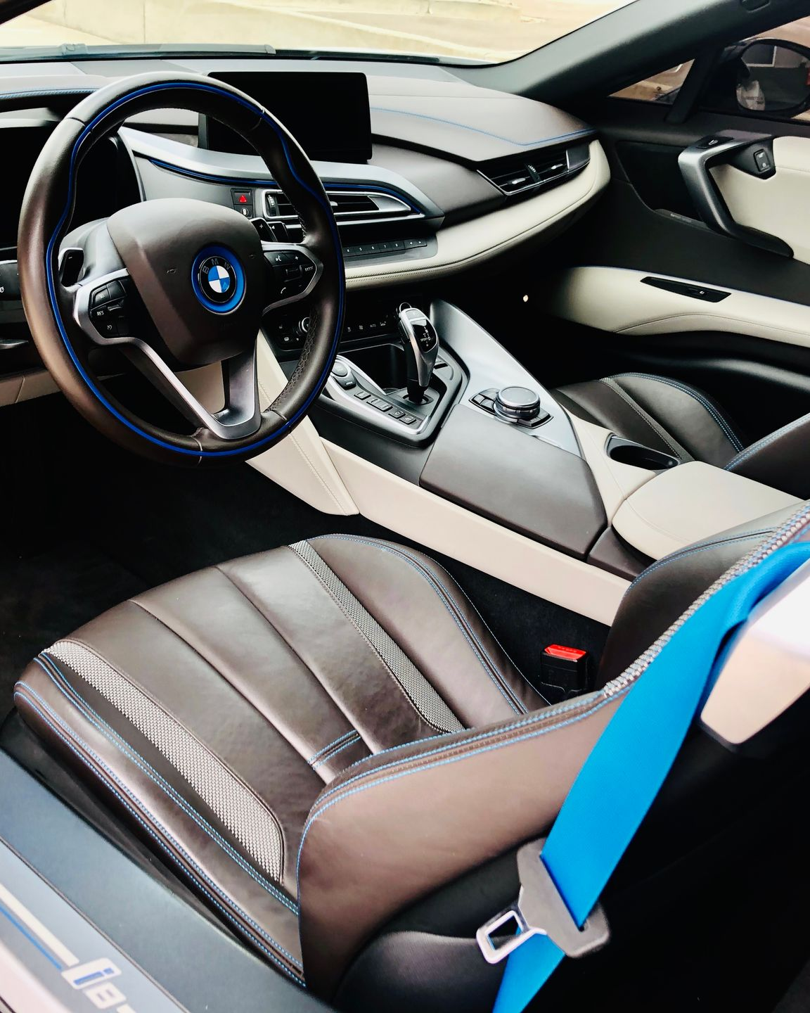 Car interior with steam cleaning nozzle spraying the dashboard and center console.