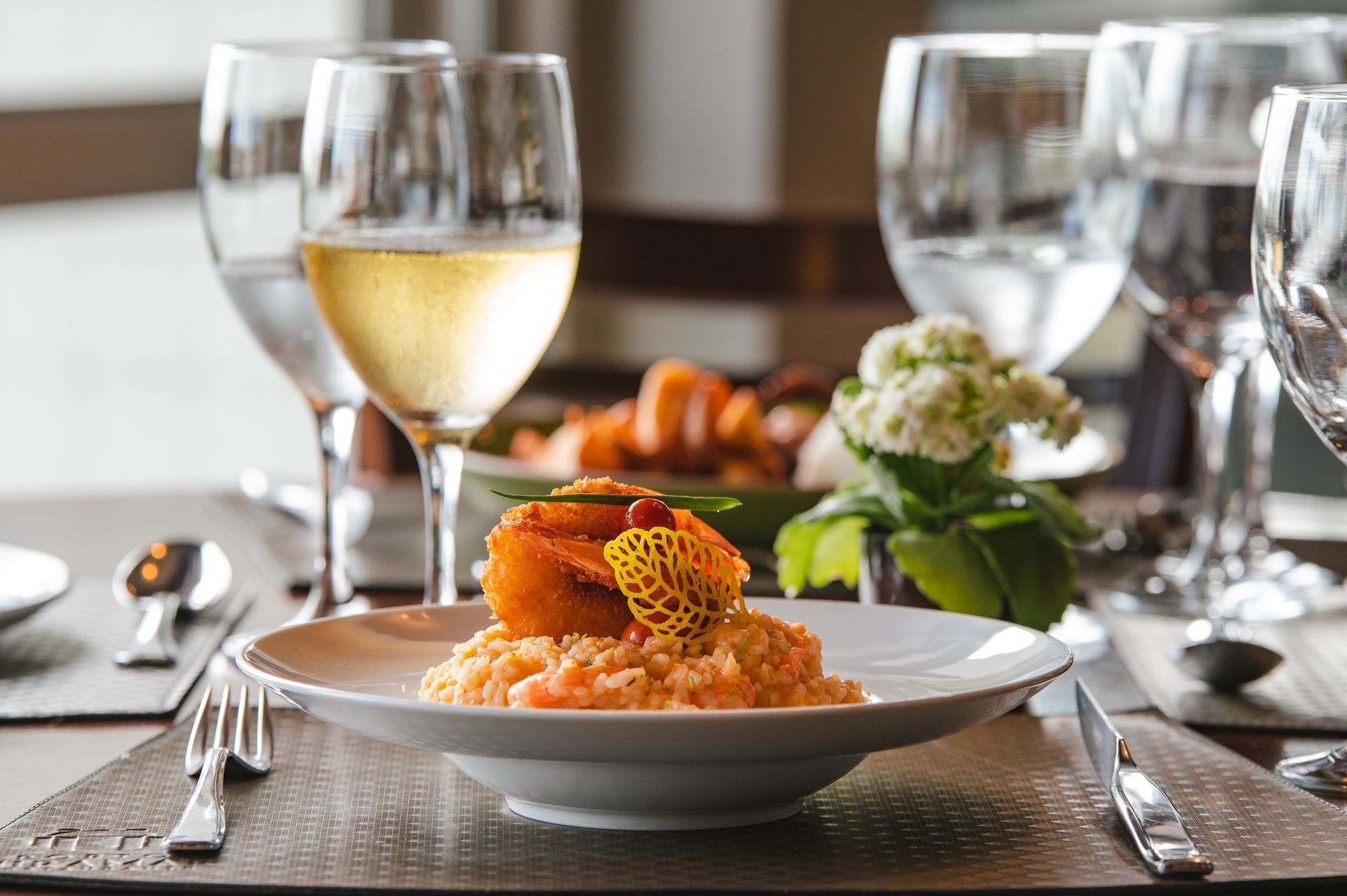 Mesa de jantar elegante com pratos gourmet, taças de vinho e salada como acompanhamento em uma refeição formal.