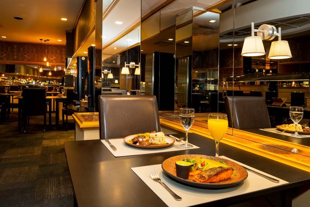 Mesa de restaurante elegante, posta com pizza e bebidas, em um ambiente acolhedor e com iluminação suave.