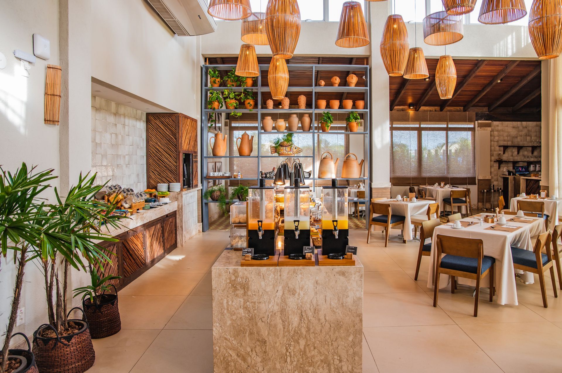 Interior de restaurante moderno com luzes pendentes, balcão de bar e mesas de jantar arrumadas.
