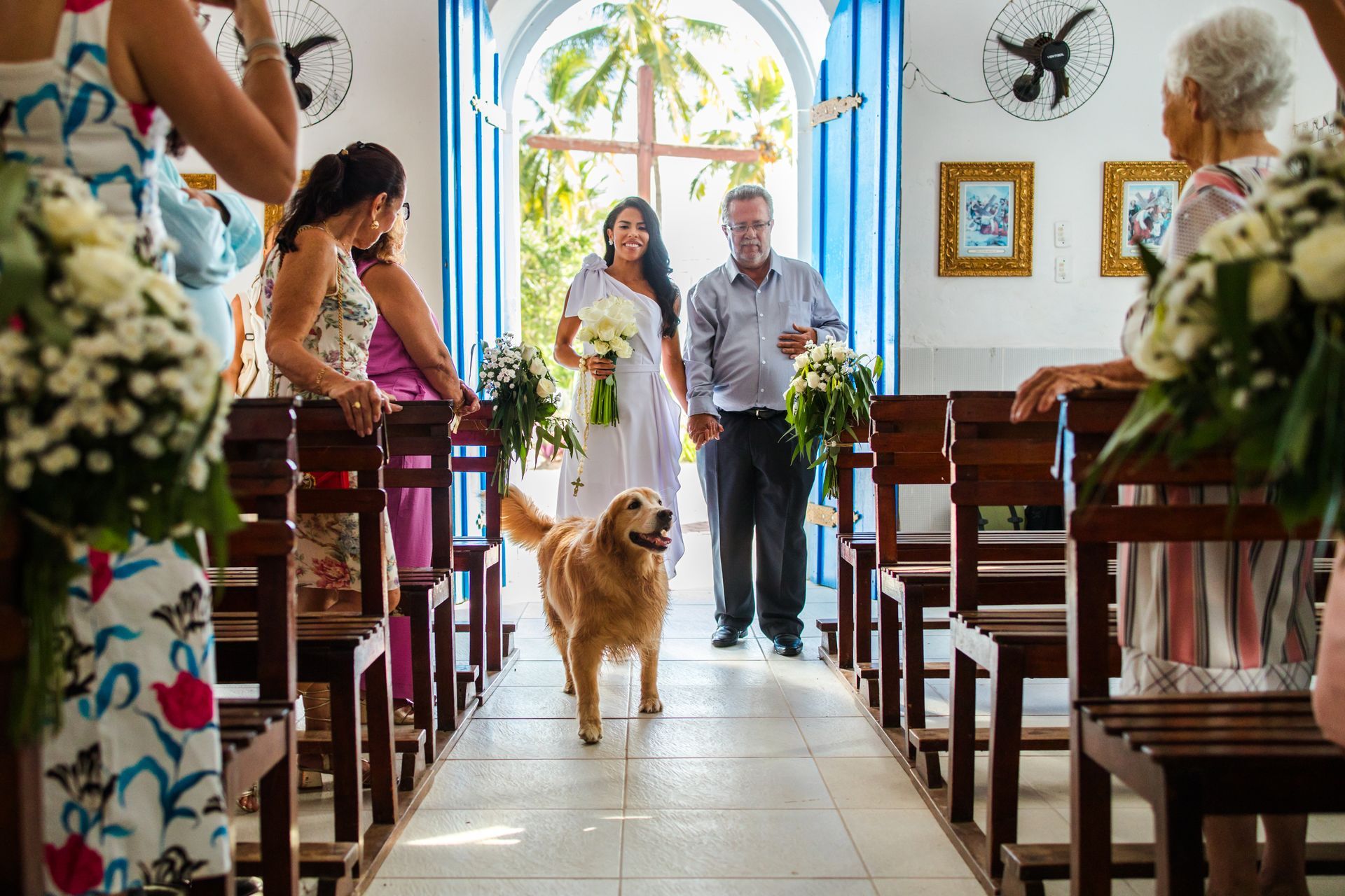 Cachorro caminhando pelo corredor da igreja com o casal entrando em uma capela iluminada.