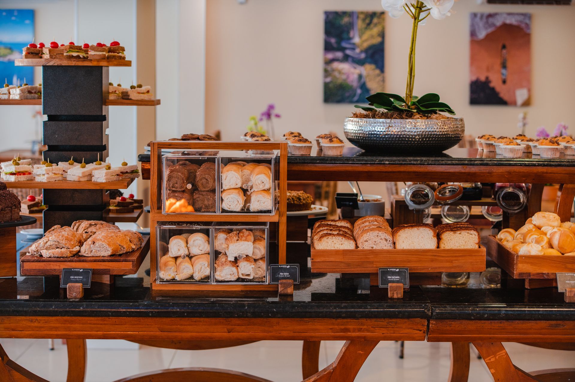Mesas de exposição de padaria com uma variedade de pães e doces em uma loja bem iluminada.