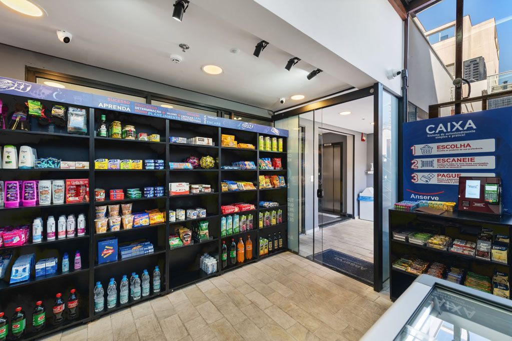 Exposição moderna de lanches e bebidas dentro de uma loja de conveniência bem iluminada, com prateleiras repletas de produtos coloridos e embalados.