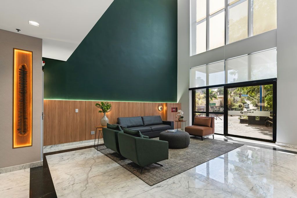 Hall de entrada moderno com parede de destaque em verde escuro, sofá preto, painéis de madeira e janelas do chão ao teto.