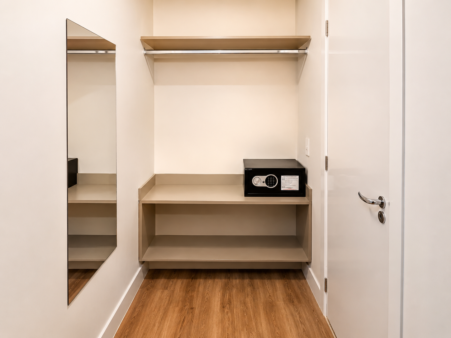 Closet vazio com piso de madeira, prateleiras, varão para pendurar roupas e espelho de parede.