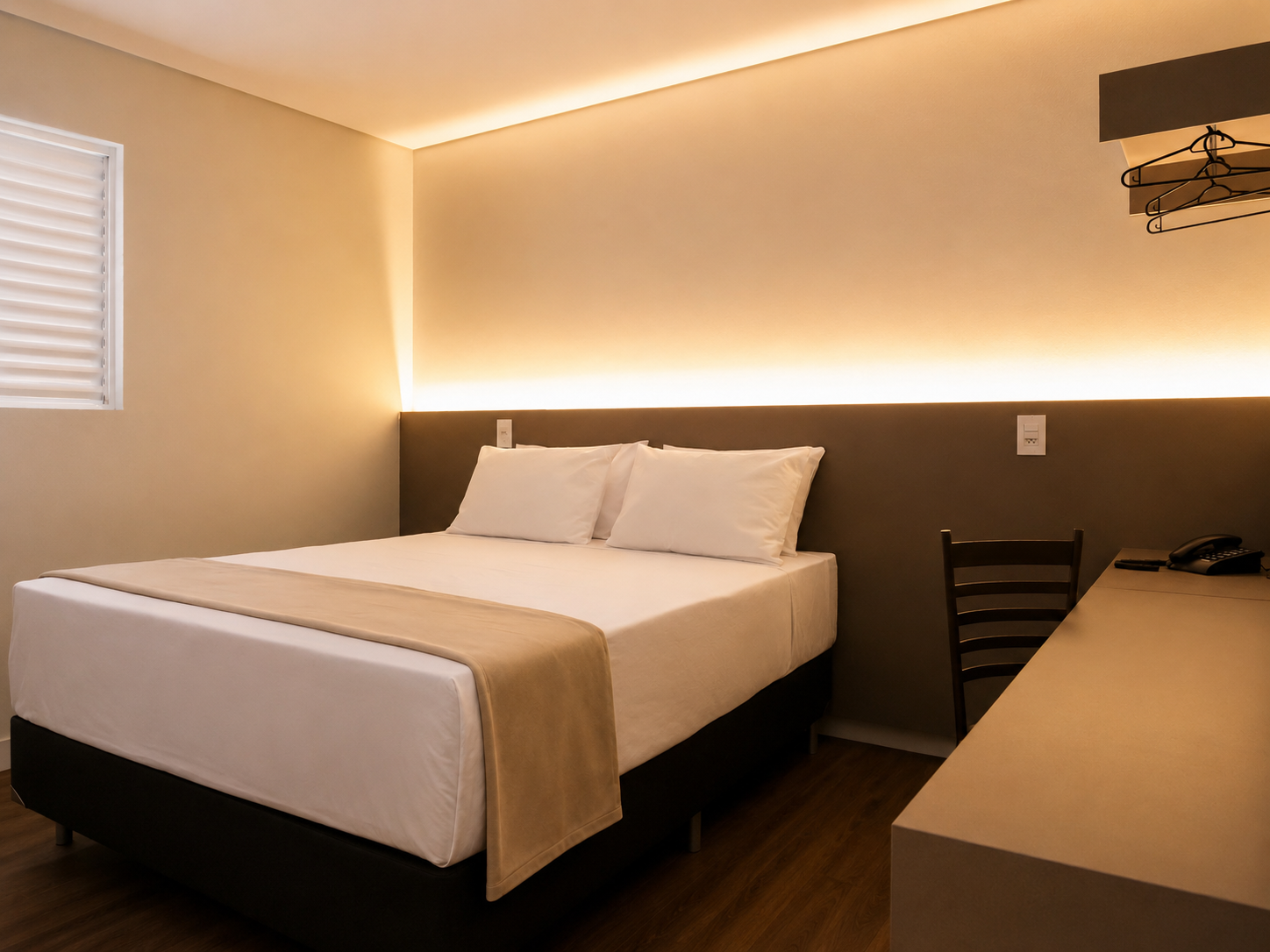 Quarto minimalista com cama, paredes bege, piso de madeira e iluminação suave nas paredes.