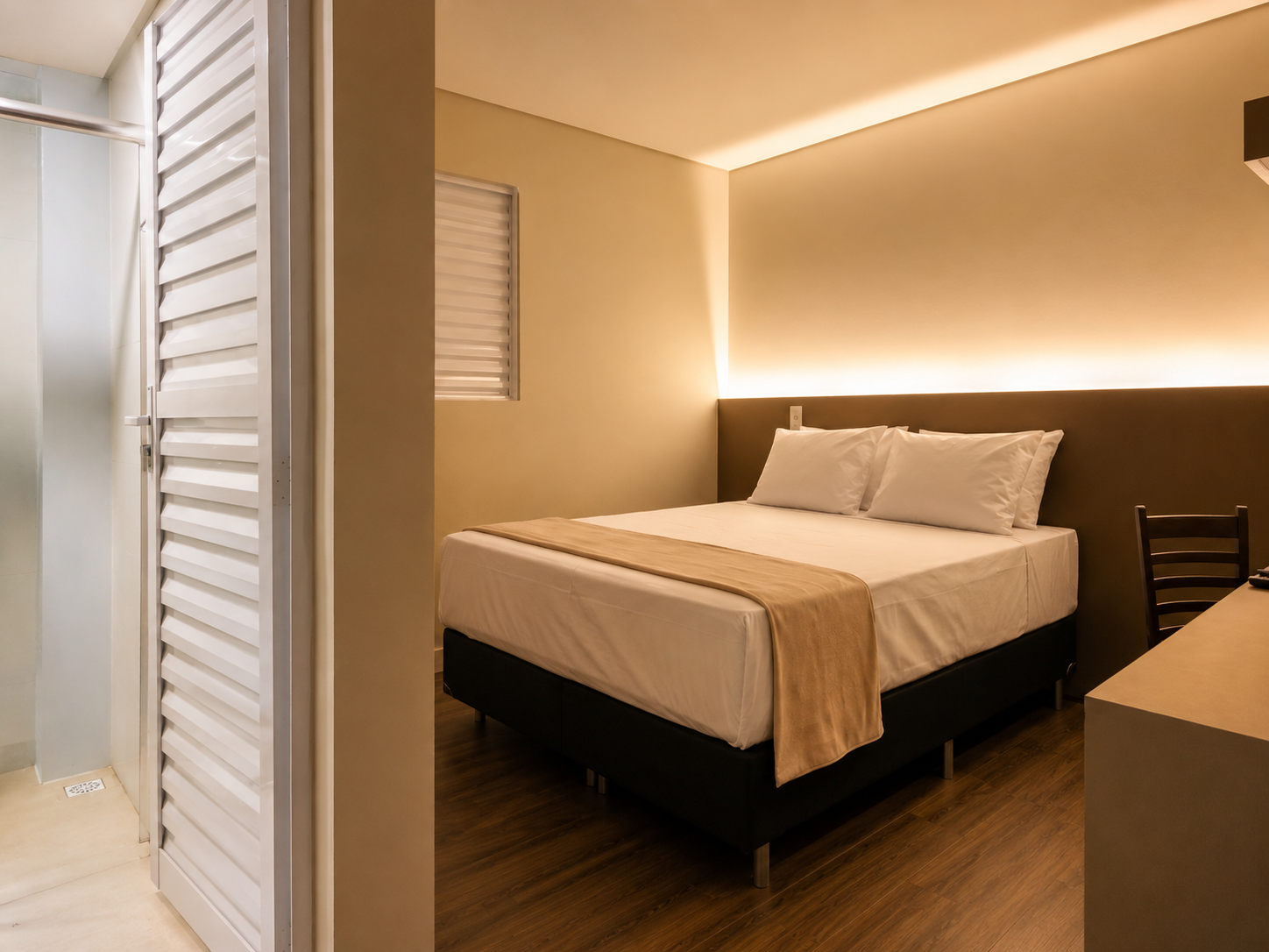 Quarto moderno com cama arrumada, iluminação aconchegante e piso de madeira.