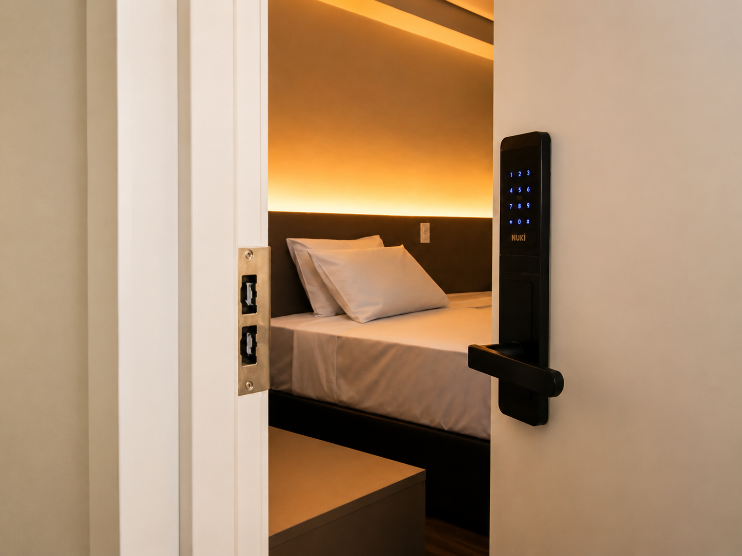 Abrir a porta do quarto com fechadura digital revela uma cama arrumada.