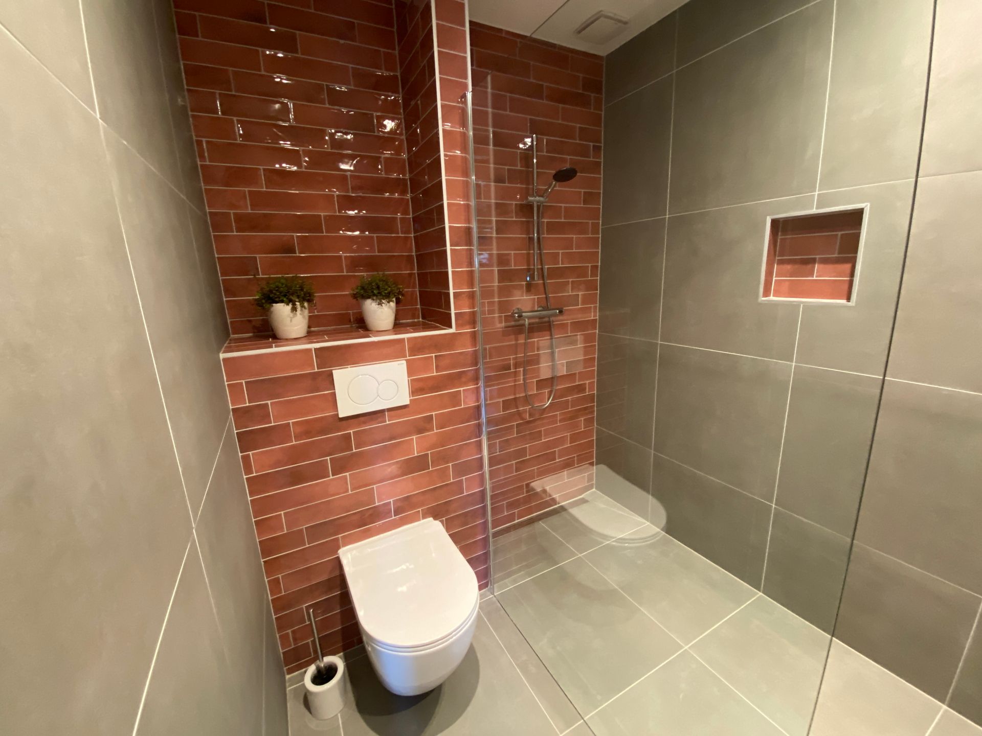 Luxe en moderne badkamer met inloopdouche, toilet, badkamermeubel, staand handdoekenrek  en radiator.  