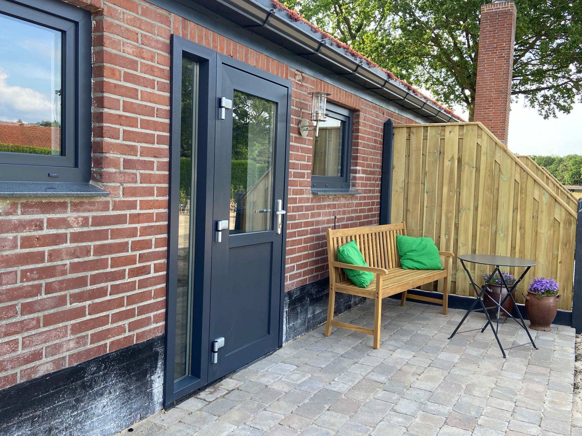 Terras met bankje en tafel. Stopcontacten voor het opladen van fietsen aanwezig. 