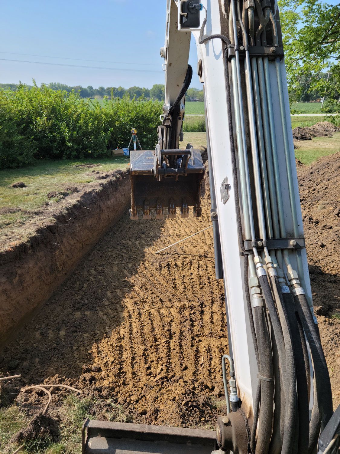a white excavator is digging a hole in the ground
