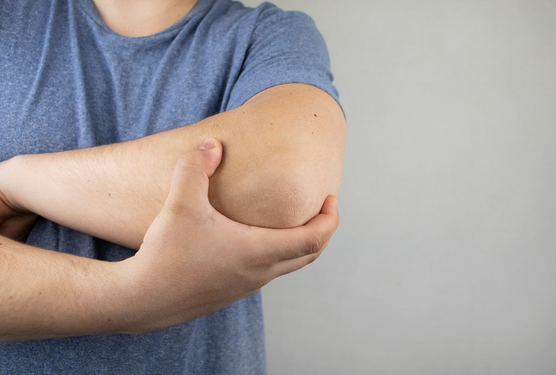 un homme se tient le coude avec sa main
