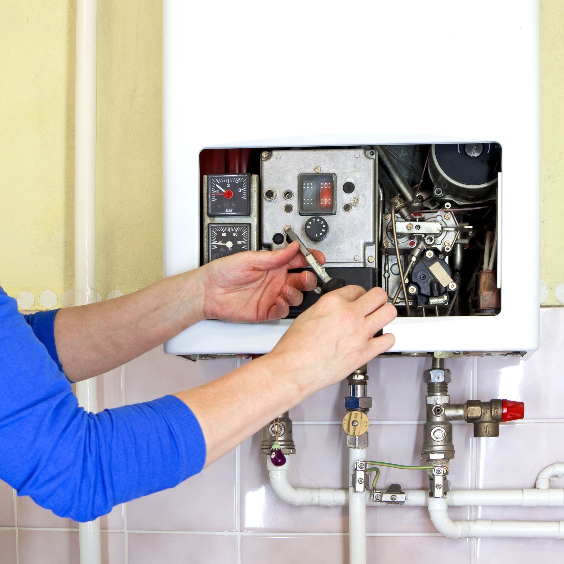 Plumber working on a gas heating system in a residential property.