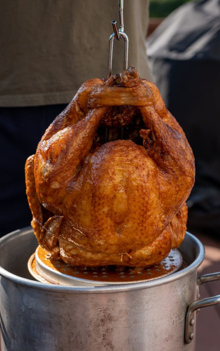 Roasted turkey on a table with people, drinks, and side dishes.