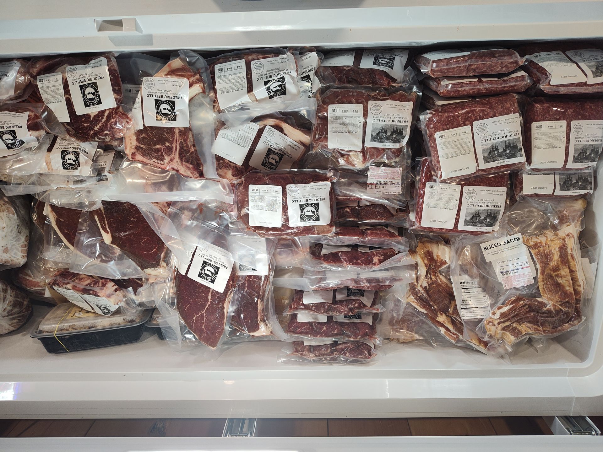 A chest freezer packed with various vacuum-sealed cuts of raw meat, stacked neatly in rows and layers.