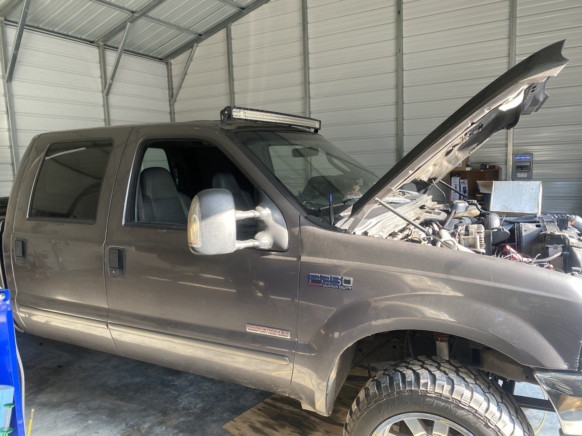 A truck with its hood up is parked in a garage.