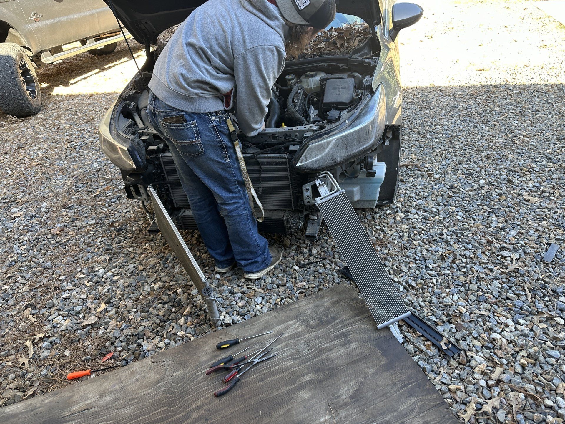 A man is working on a car with the hood up.