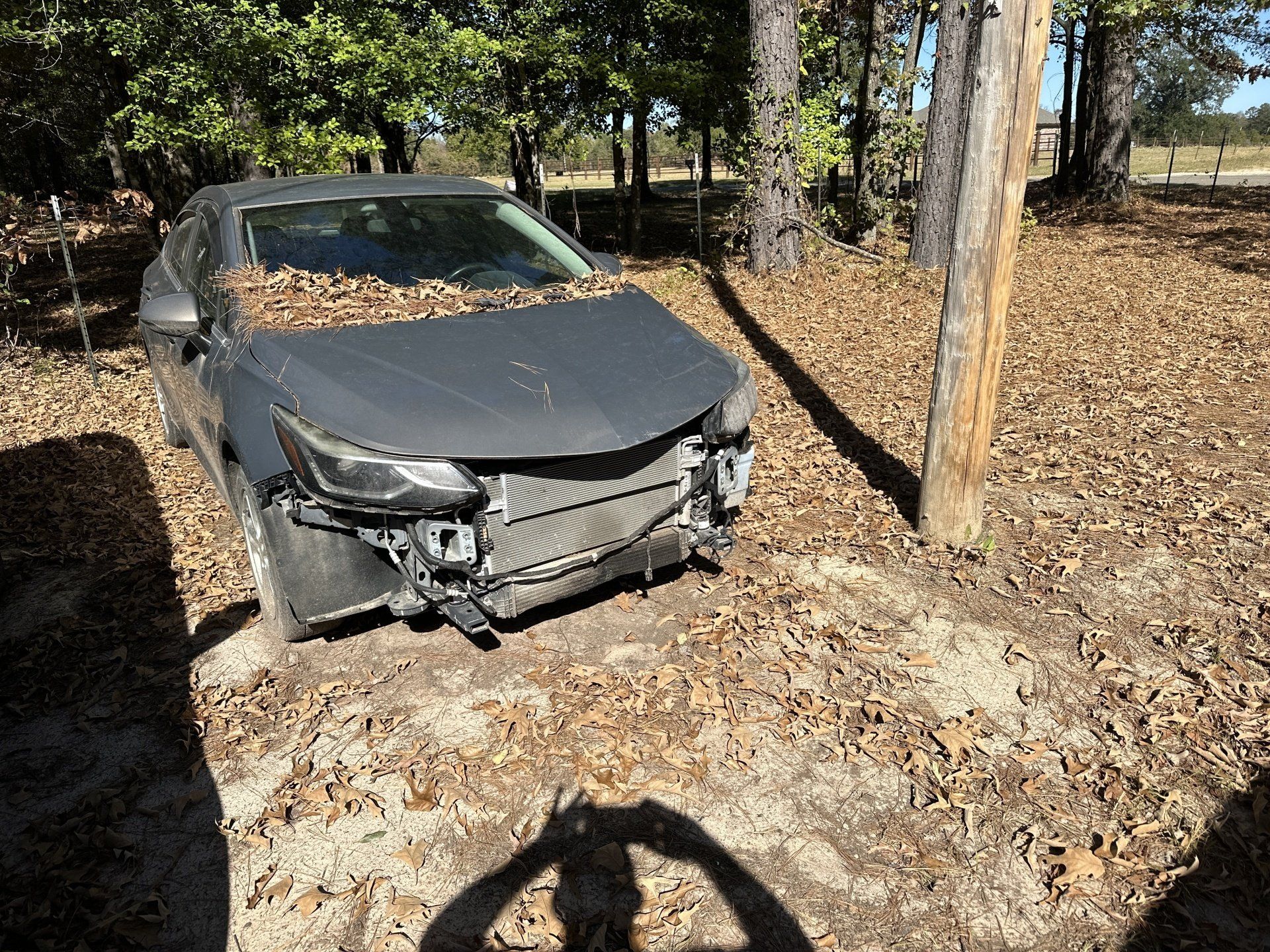 A black car is sitting in the dirt next to a tree.