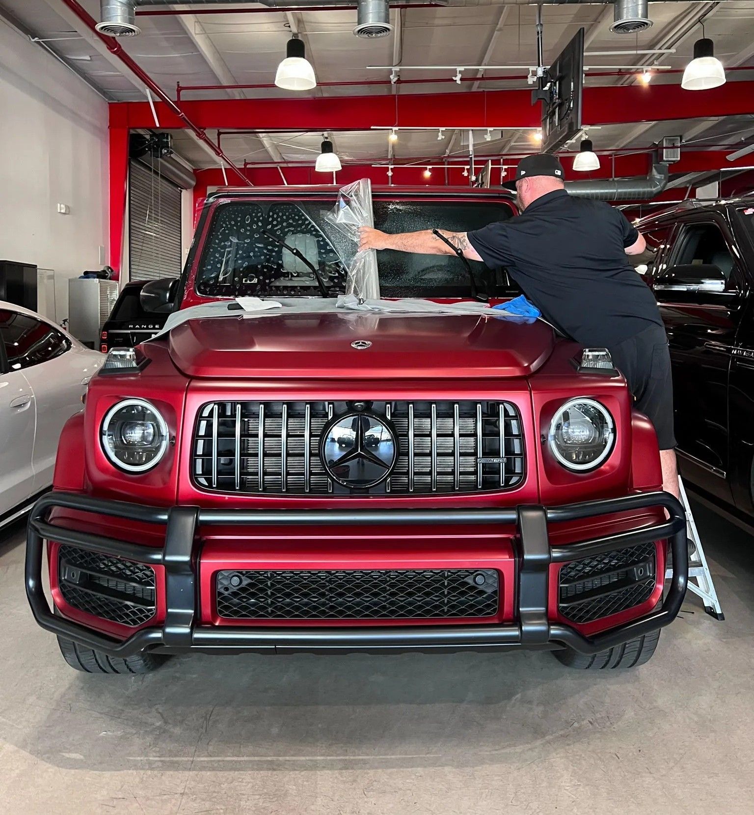 A white mercedes benz g63 amg is parked in front of a building.