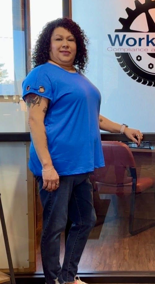 Woman in blue shirt standing by a glass wall with a Work logo in the background.