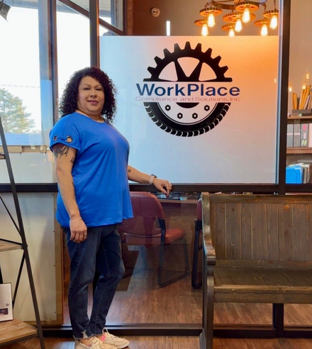 Person in blue shirt standing beside a WorkPlace sign indoors