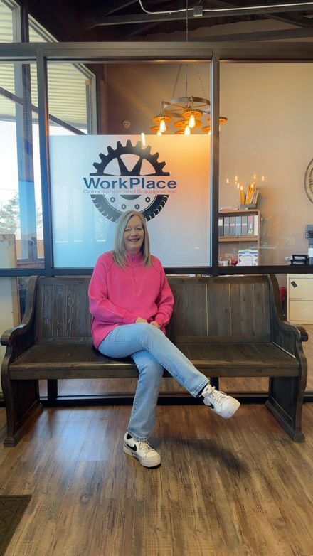 Woman in pink sweater sitting on a wooden bench inside a Workplace café lounge