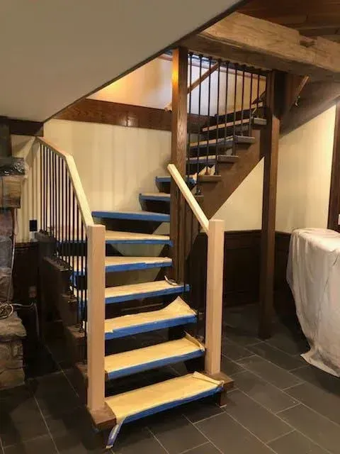 Narrow indoor staircase with blue treads and a spiral staircase under slanted ceilings.