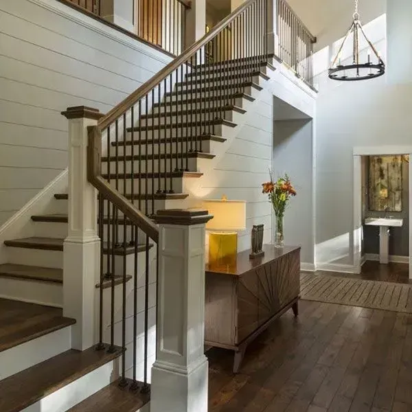 Bright foyer with curved staircase, dark hardwood floors, console table, and hanging chandelier
