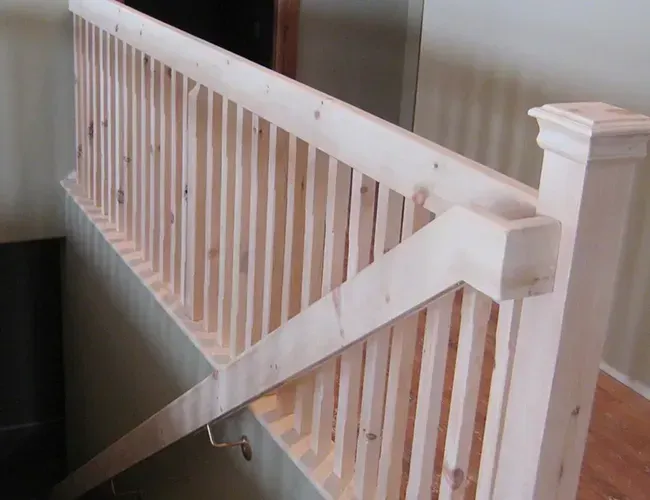 White wooden stair railing with a diagonal support brace in an indoor hallway.