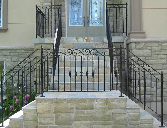 Front steps of a house with iron railings and stone stairs leading to double doors