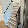 Wooden staircase with black handrails in a narrow indoor hallway