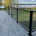 Glass railing on a gray wooden deck overlooking a grassy lakeside view